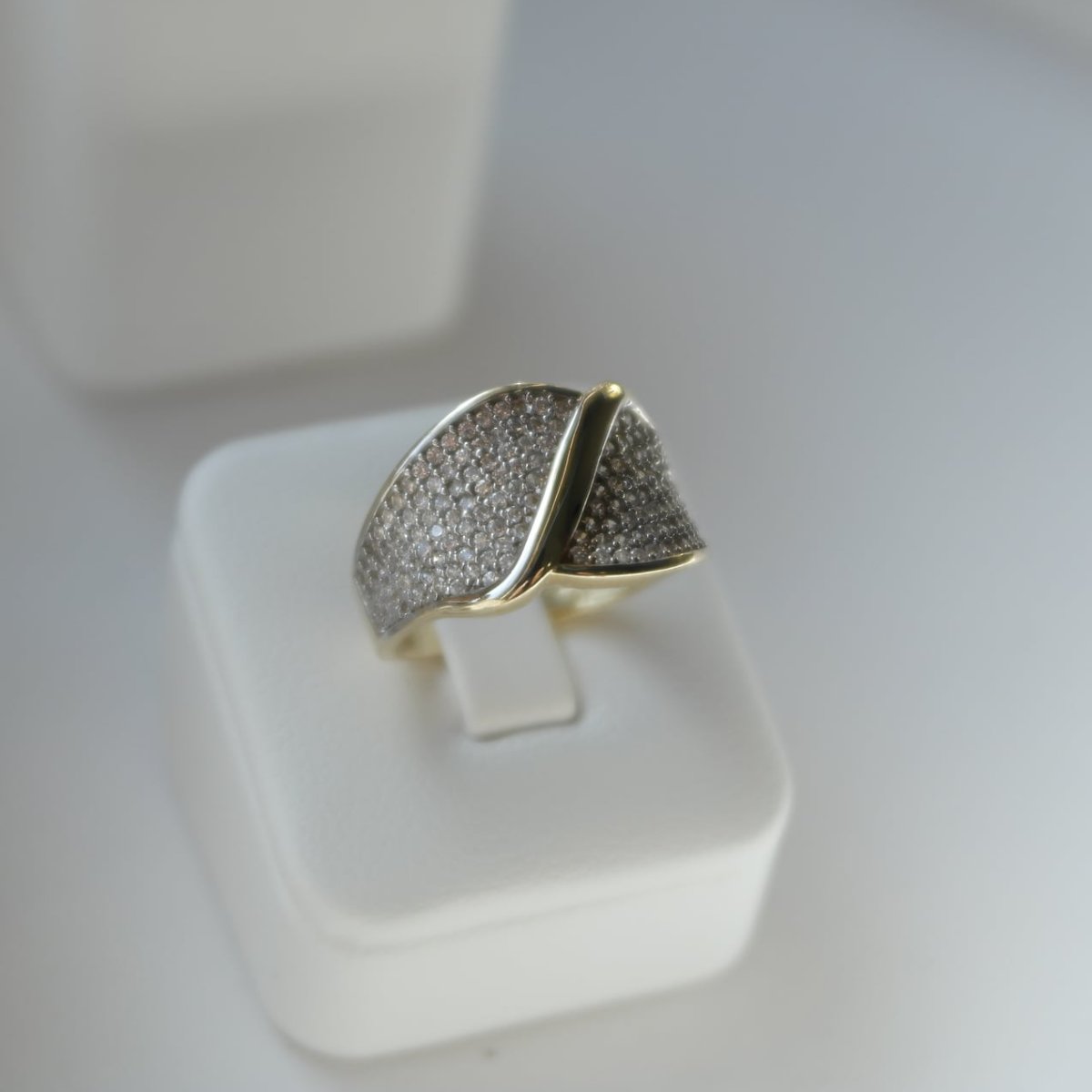 Szeroki złoty pierścionek z gęsto osadzonymi drobnymi kamieniami.